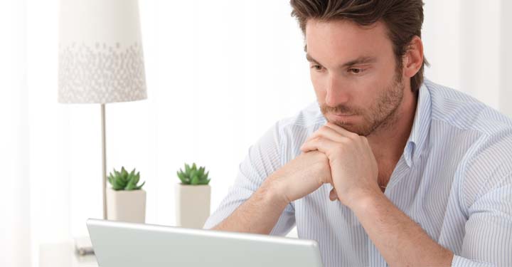 A man sitting at a desk and researching on a laptop the legal consequences for remarrying before getting a divorce