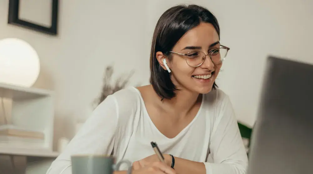 A young Michigan business owner with glasses conducts a Michigan business search at her desk.