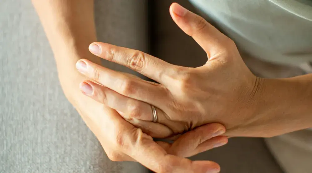 A woman wrings her hands, her wedding band clearly showing. People considering divorce in Illinois need to follow the state's unique guidelines.