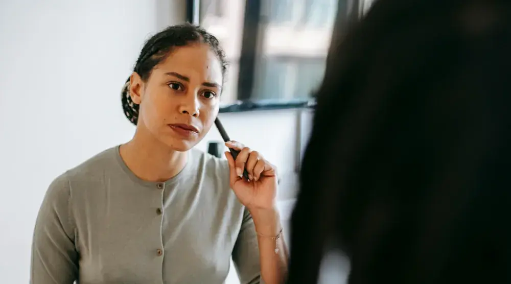 A mixed race woman with braids taps a pencil on her cheek as she listens closely to her divorce lawyer.