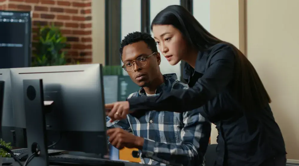 Two people point to a computer screen. Learn how to protect your business against brand infringement and what to do if it affects your business assets.