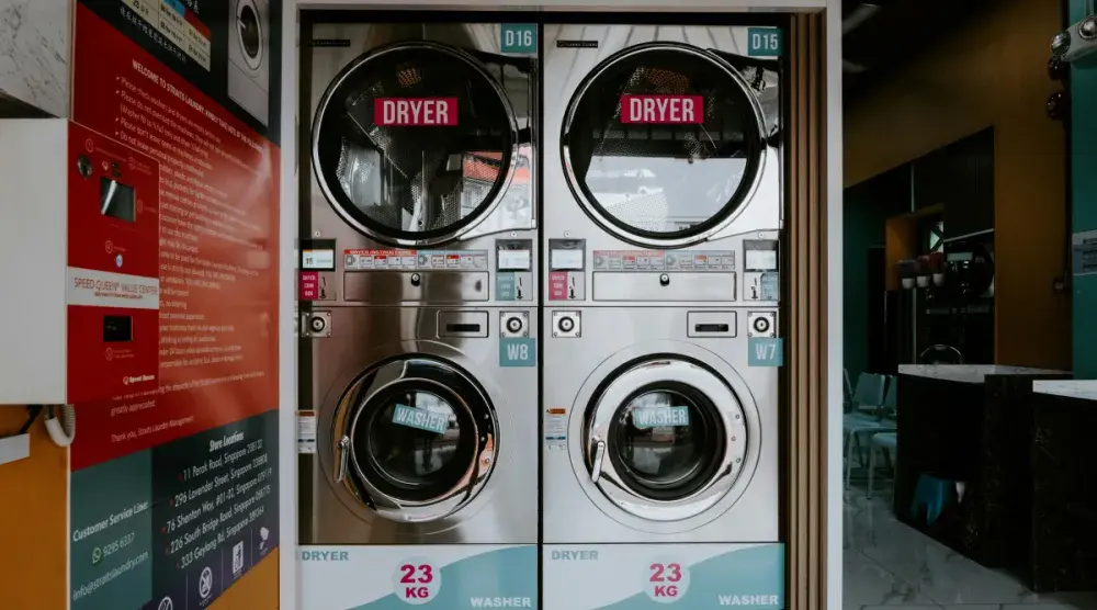 Dryers are stacked on top of washing machines in a laundromat. Learn about the startup costs, business structures, and how to prepare before opening your laundromat.