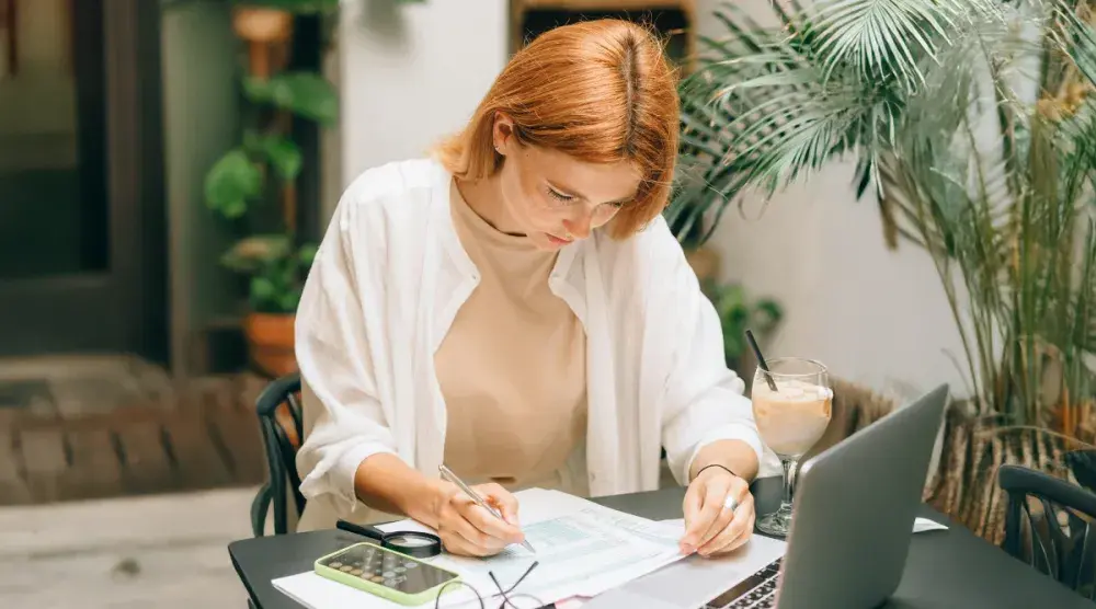 A Florida business owner sits at her desk at an open-concept coworking space and reads over financial documents for her Florida annual report.