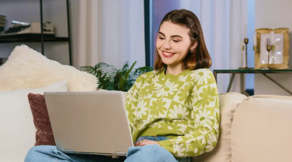 A woman sits on her couch and looks up an EIN on her laptop.