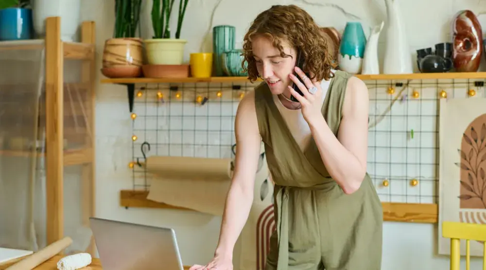 The owner of a small business in Illinois talks to a customer on her phone while checking an online order.