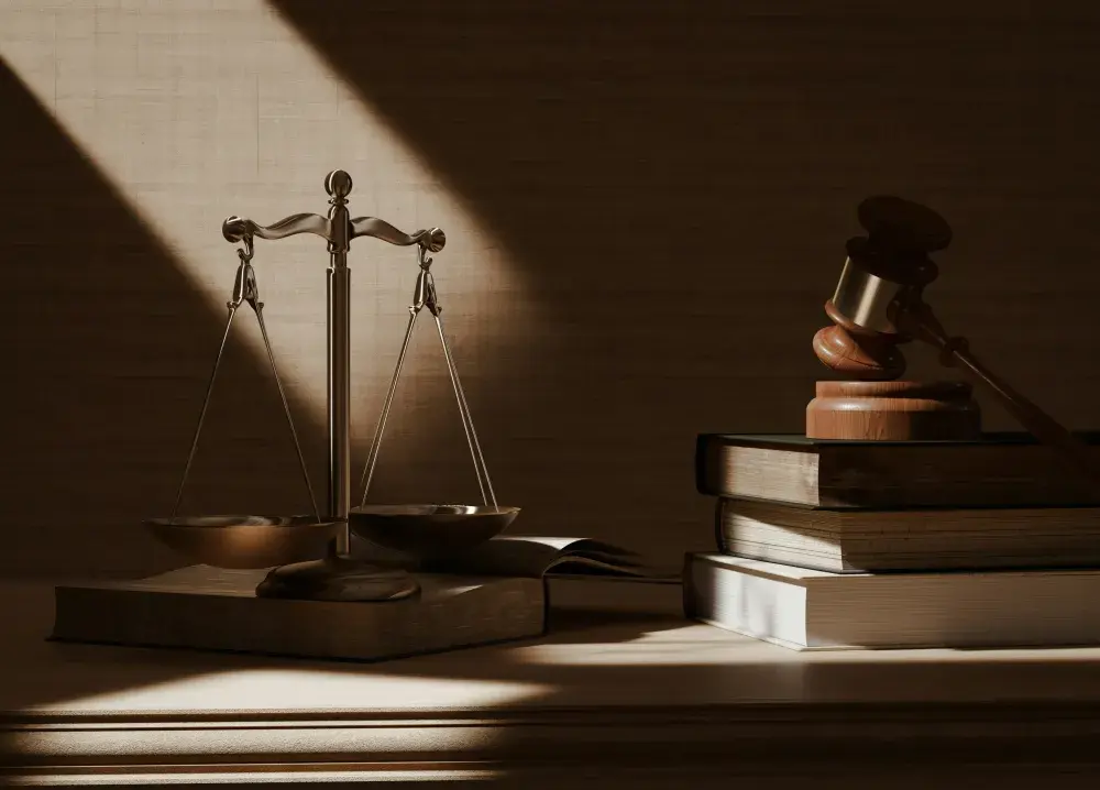 A set of scales on a desk next to a stack of law books and a gavel.