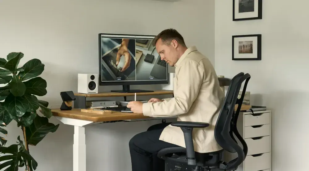 A man sits at his desk and carefully reviews his patent design as he fills out his patent application.