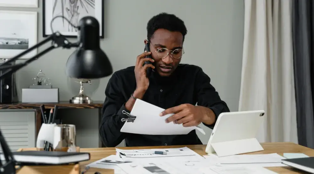 A small business owner in Wyoming talks to his attorney on the phone as he reads information regarding the business' annual report.