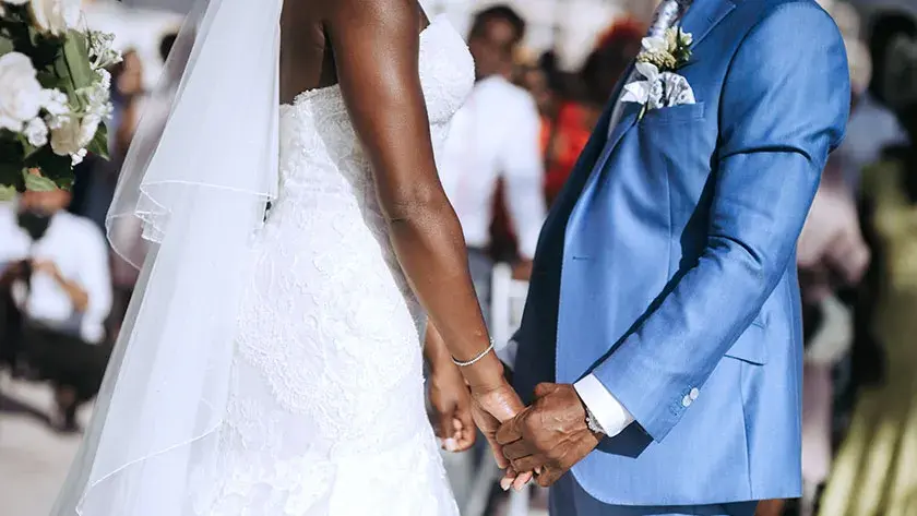 A bride and groom hold hands during their wedding ceremony.