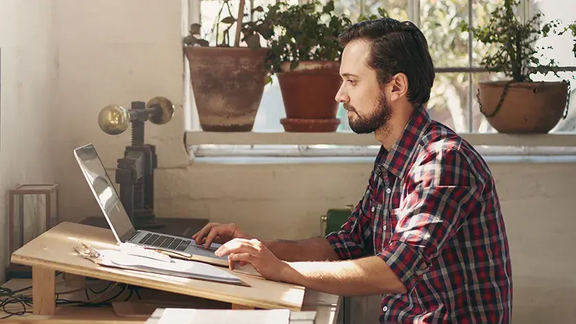 A man who is a small business owner sitting at a desk and researching on a laptop how much it costs to file for bankruptcy