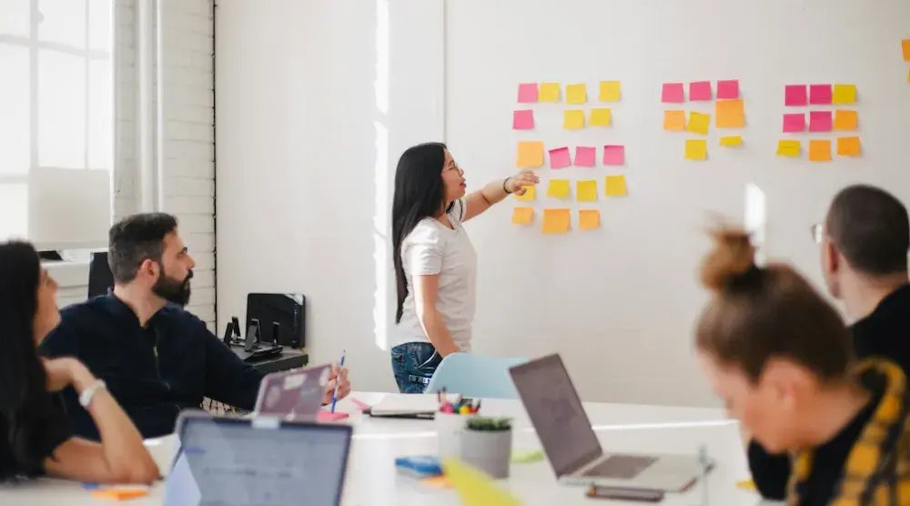 People sit around a conference room table as a woman leads the meeting at the front of the room. anyone who willfully violates the BOI reporting obligations can face criminal penalties, including up to $10,000 in fines and/or two years of imprisonment.