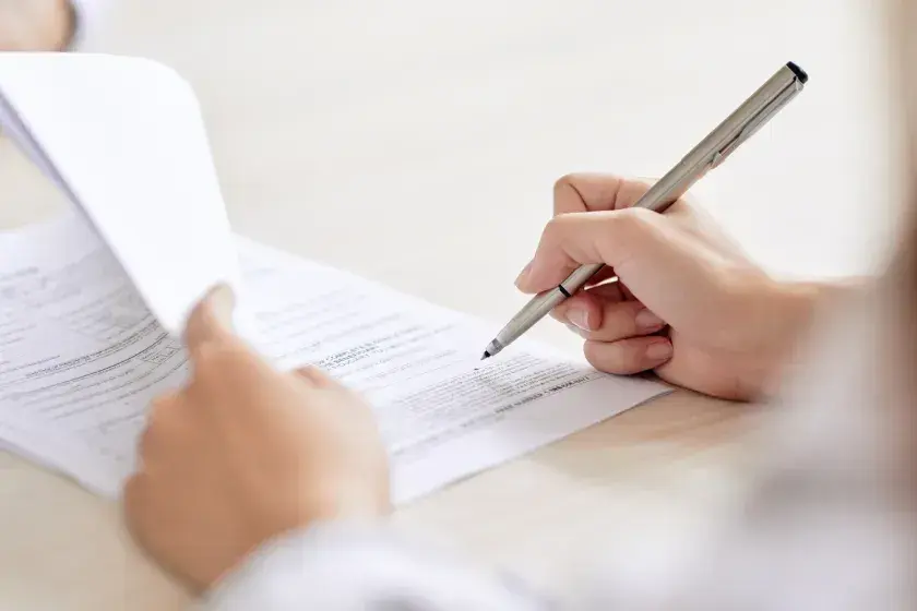 A person seated at a desk signs divorce paperwork. Contested and uncontested divorce are two common ways to dissolve a marriage. 