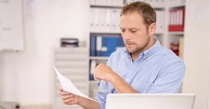 Man holding a piece of paper and reading from it