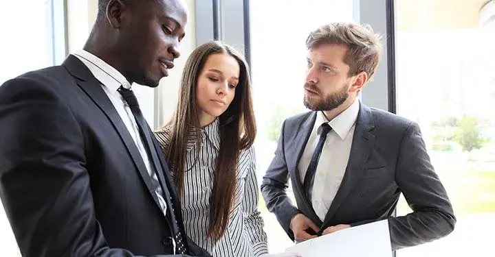 Two businessmen and one businesswoman looking at paperwork