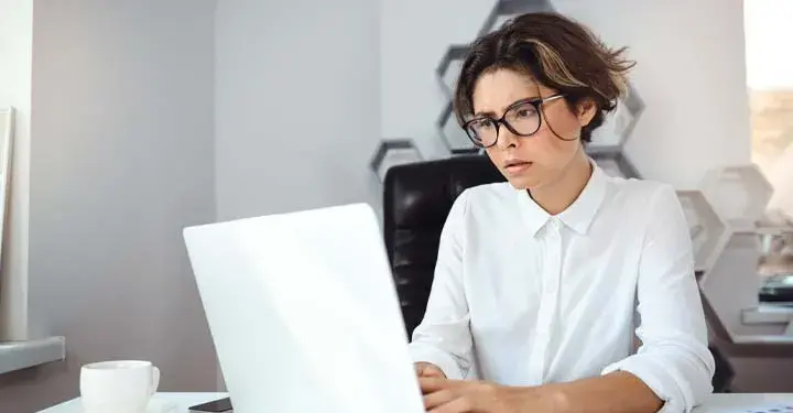 Woman sitting at desk looking intently at laptop