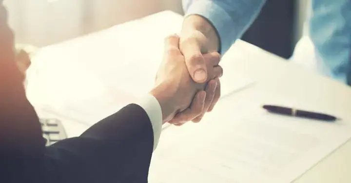 Businesspeople shaking hands over documents and pen