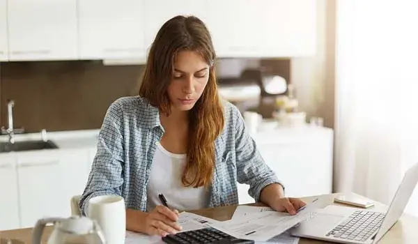 Woman doing paperwork in her kitchen <a href=