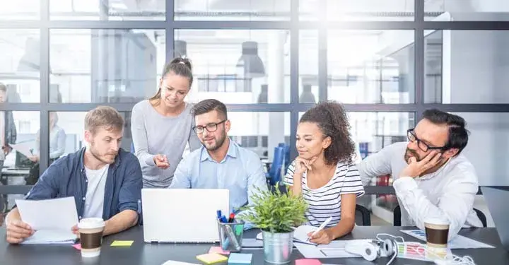 Coworkers sitting at a desk looking at one laptop