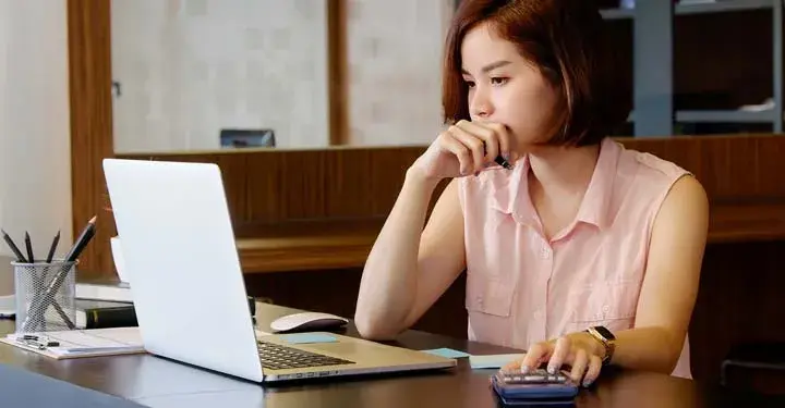 Woman at desk looking intently at laptop