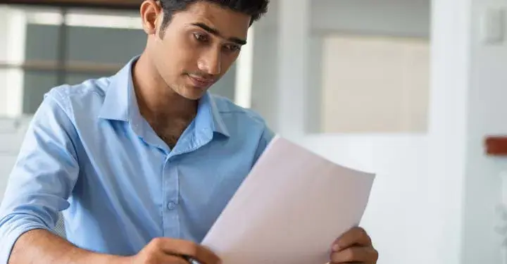 Man in button up shirt holding paper