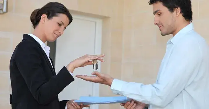 Woman in suit putting keys into man's hand