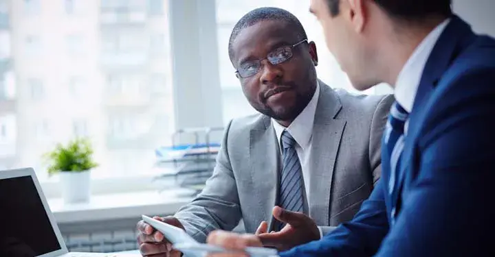 Two men in suits talking in office