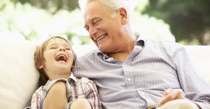 Grandfather and grandson laughing on a couch