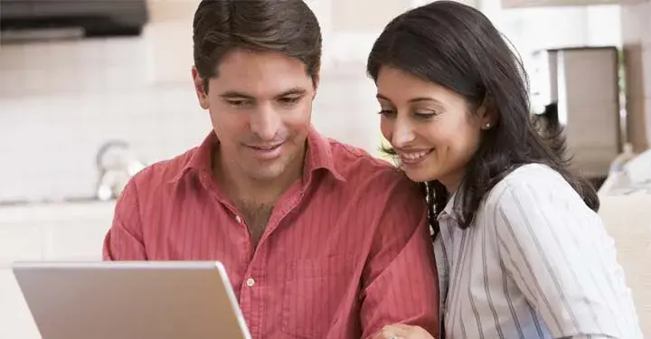 Couple in kitchen gazing at iPad