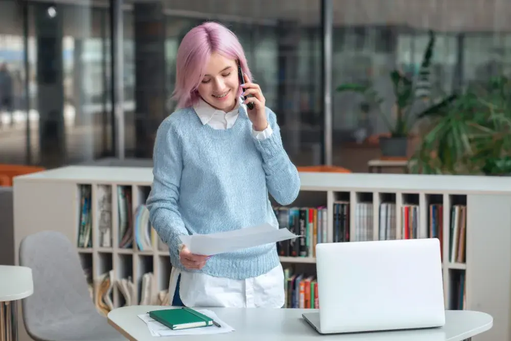 A small business owner talks on her cell phone while looking over a document. Starting in 2024, ownership interests must be reported to the U.S. Treasury Financial Crimes Enforcement Network (FinCEN).