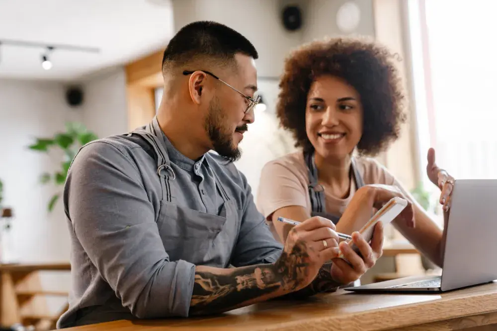 A man and woman, both wearing aprons, sit at a counter and chat about their Beneficial Ownership Information Report. The new Corporate Transparency Act addresses the national security concern that exists when unknown foreign entities control companies in the U.S. 