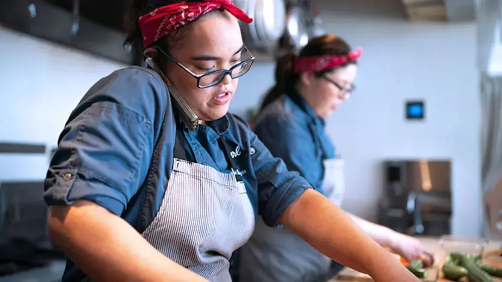 A chef takes an order over the phone as she works in the kitchen of her restaurant that is a DBA. A DBA, or “assumed name,” allows businesses in Texas to operate under a name different from their legal name. 