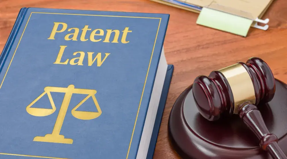 A book on patent law sits on a desk next to a gavel and sound block