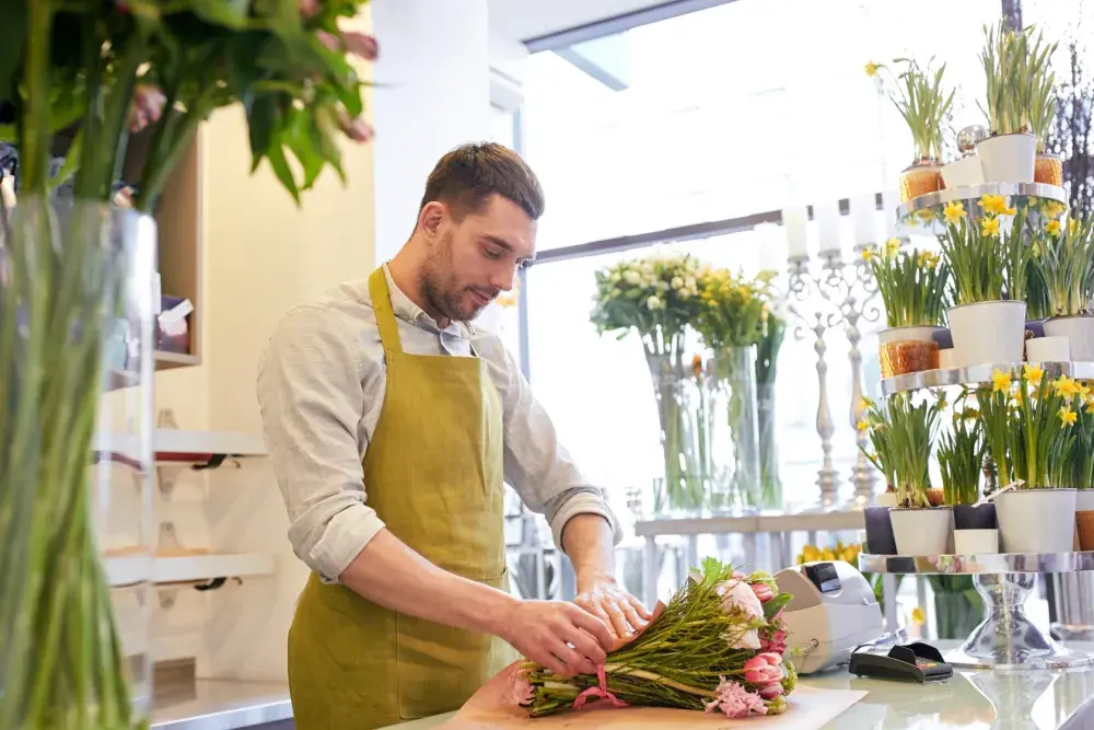 A florist wraps up an order of fresh flowers in his shop. 