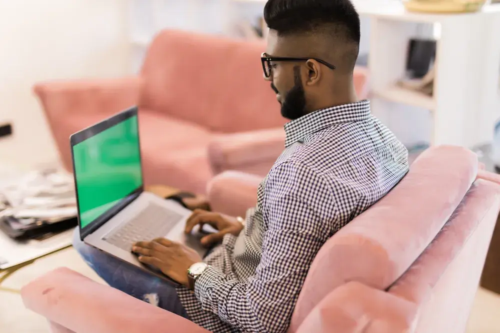 A man works on his laptop in a room with pink furniture. He reads that Texas law offers robust asset protection to LLCs, making it an attractive option for business owners. 