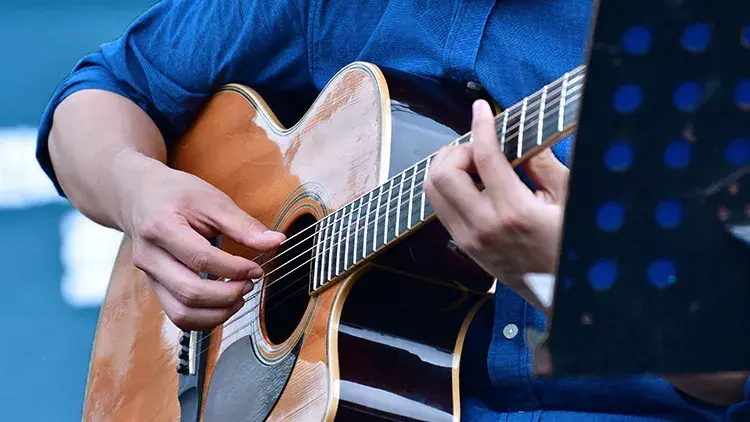 man in blue shirt playing guitar in the studio