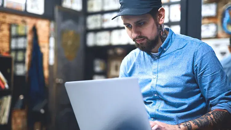 man with tattoos looking at laptop