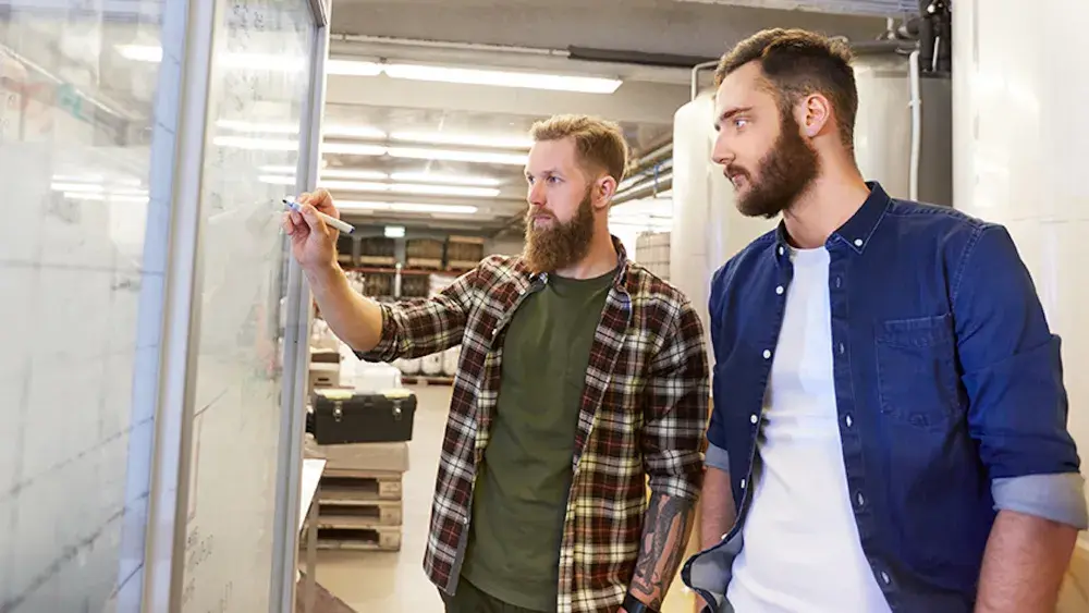 The owners of a new brewery discuss strategy and write ideas on a whiteboard before forming their Florida LLC. The cost of a Florida LLC can range from $125-$538. 