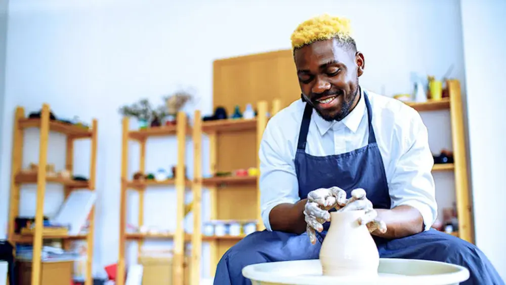 A potter works at his wheel in the workshop where his new LLC is based.