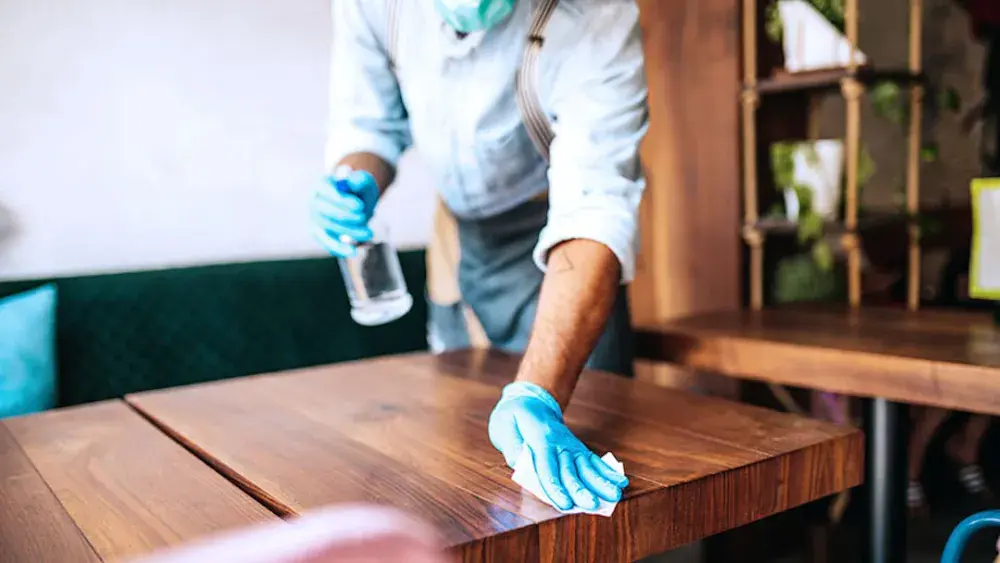 A N.Y. restaurant owner and single-member LLC cleans off a table. Disadvantages of a N.Y. LLC include higher sales taxes, higher state taxes, and high startup fees.