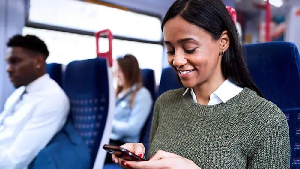 A woman on a bus checks her smartphone for her state's tax code regarding trusts.