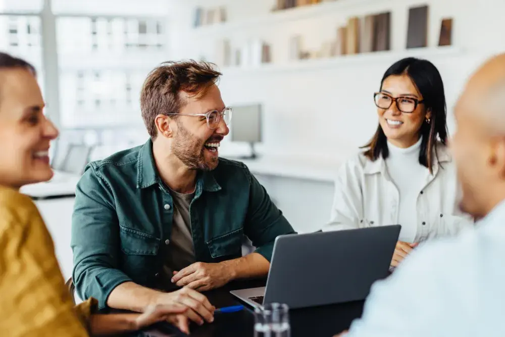 Owners of a new small business sit around a conference table and have a laugh as they celebrate their trademark registration. While registering your business or LLC name does not provide protection in the way that a trademark can, you should still put care into choosing the name.