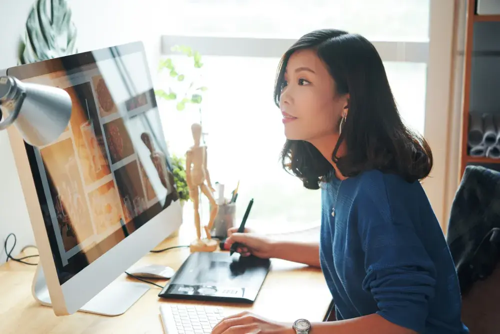 A graphic artist works at her desktop computer in her office as she considers trademark registration. Almost all trademark submissions must be submitted through an electronic application system.