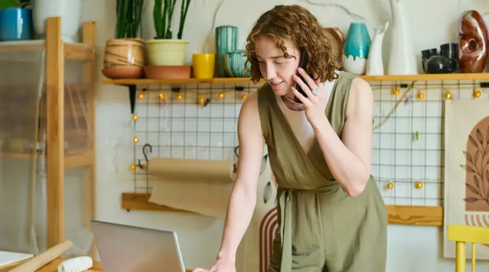 A woman in her kitchen on the phone getting information about how to get a Washington state business license