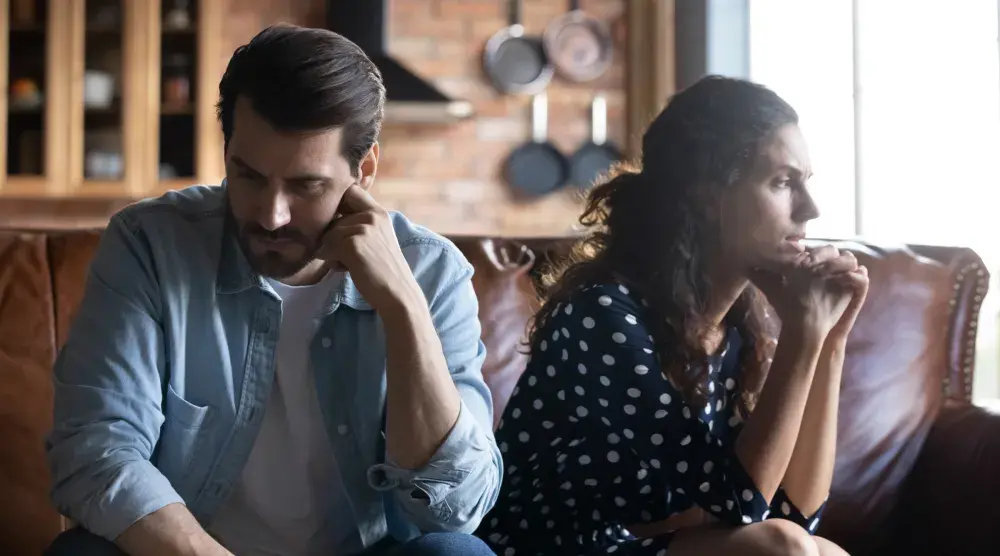 A couple sitting on a couch looking away from each other who is considering trial separation