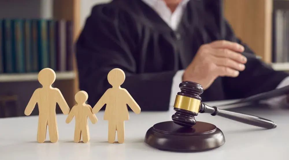 A judge reads over papers next to a set of wooden figurines depicting a family. Judges are particularly discerning when it comes to alimony in Texas.