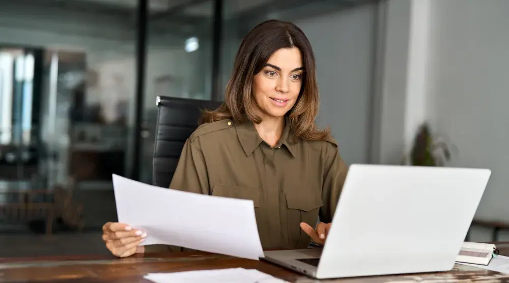 A woman sits at her desk and reviews a letter of testamentary document.