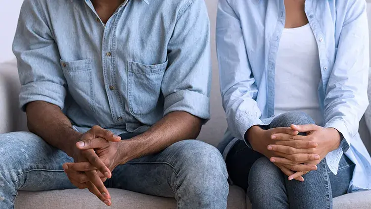 Man and woman sitting side by side with hands crossed