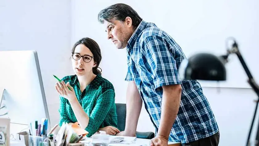 man-and-woman-discuss-business-looking-at-monitor in work room