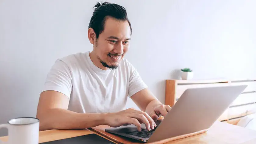 man-smiling-typing-on-laptop