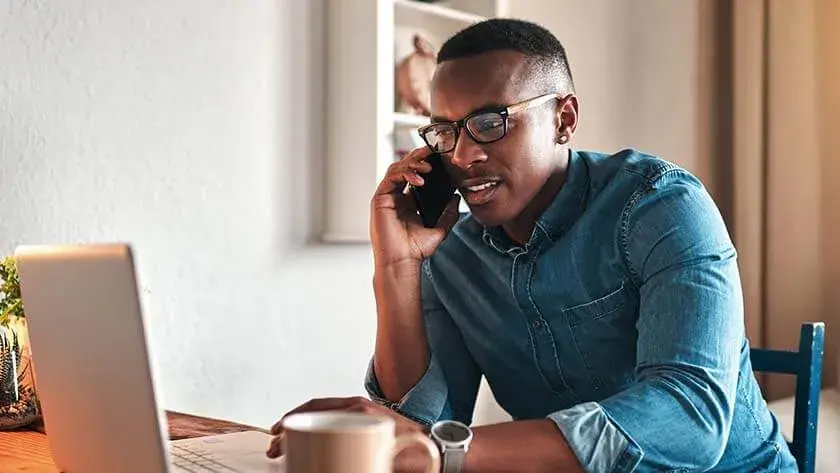 man-talking-on-phone-in-front-of-laptop